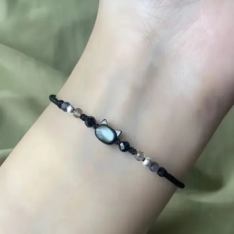 Bracelet with cat-shaped charm on a wrist against a neutral background