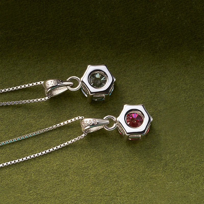 Two silver hexagonal pendants with gemstones on a green background