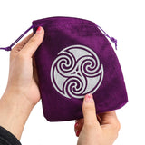Purple drawstring bag with a silver triskele symbol held by a hand on a white background
