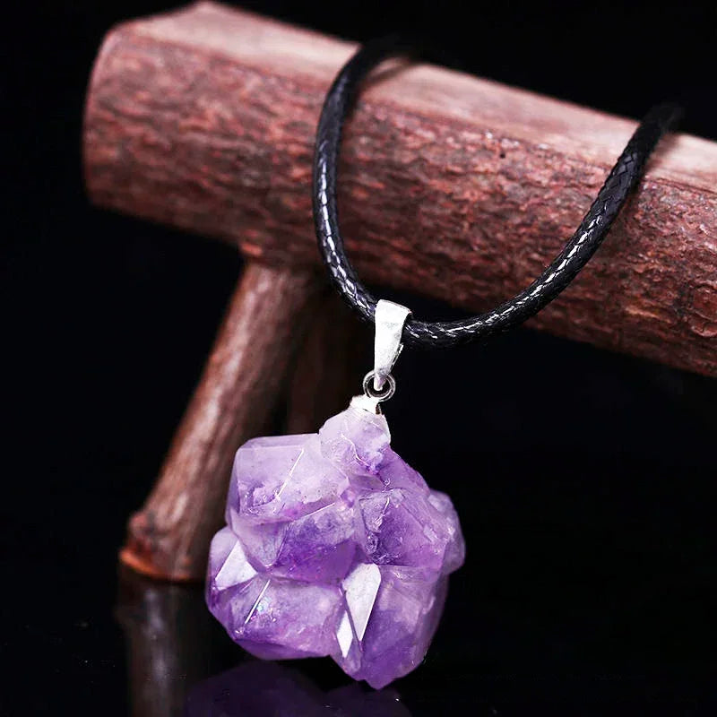 Purple crystal pendant on a black cord against a dark background