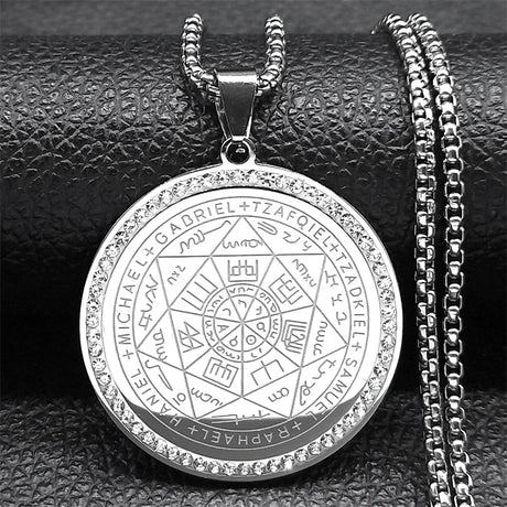 Silver pendant with intricate designs and text on a dark textured background