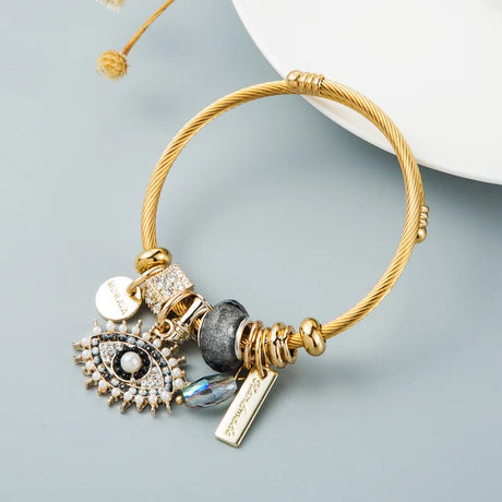 Gold bracelet with various charms on a light gray background