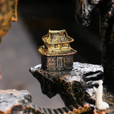 Small golden temple figurine on a dark rock surface