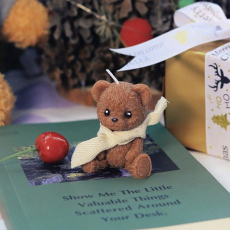 Small teddy bear with a scarf on a book titled 'Show Me The Little Valuable Things Scattered Around Your Desk'.