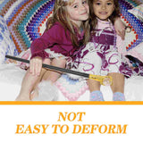 Two young girls sitting on a colorful blanket with a wand, wearing matching dresses.
