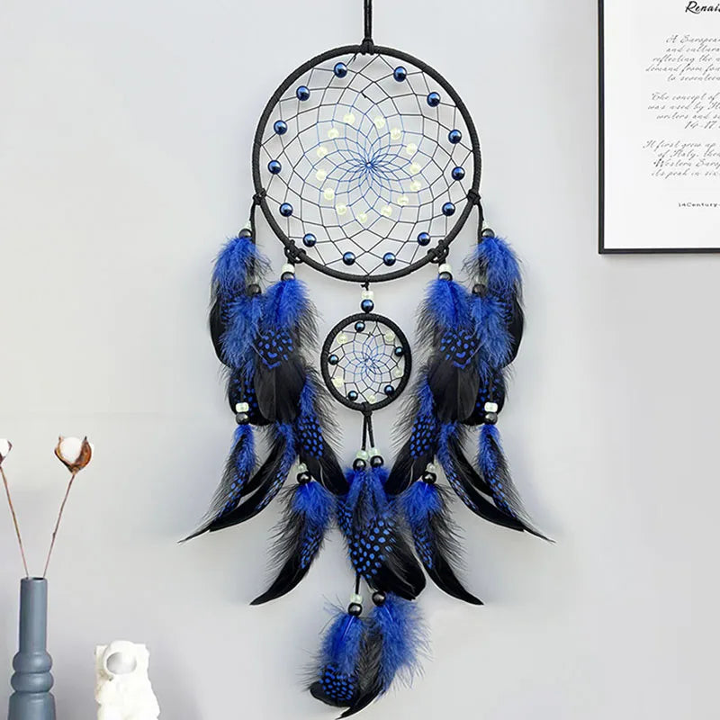 Blue and black dreamcatcher hanging on a white wall.