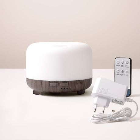White diffuser with wooden base, remote control, and power adapter on a light surface.