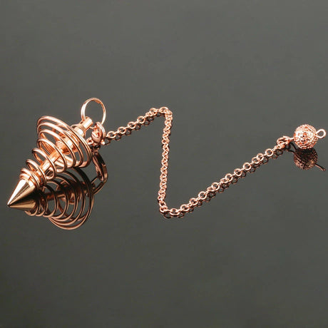 Rose gold spike pendant on a chain against a dark background