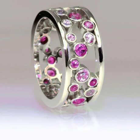 Silver ring with pink gemstones on a light gray background