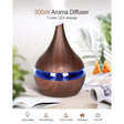 Wooden aroma diffuser with blue LED light on a table with books and oranges.