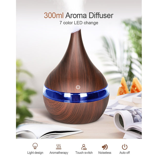 Wooden aroma diffuser with blue LED light on a table with books and oranges.