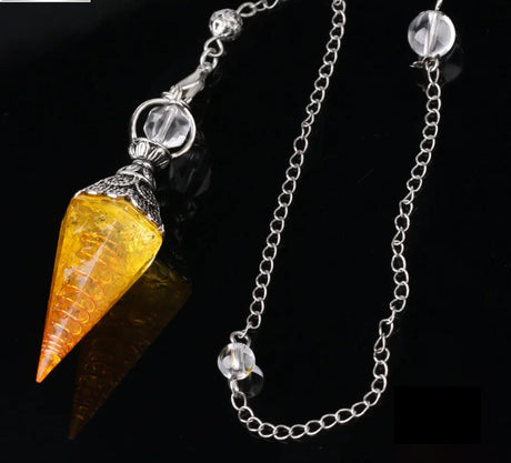 Crystal pendulum with yellow cone and silver chain on a dark background
