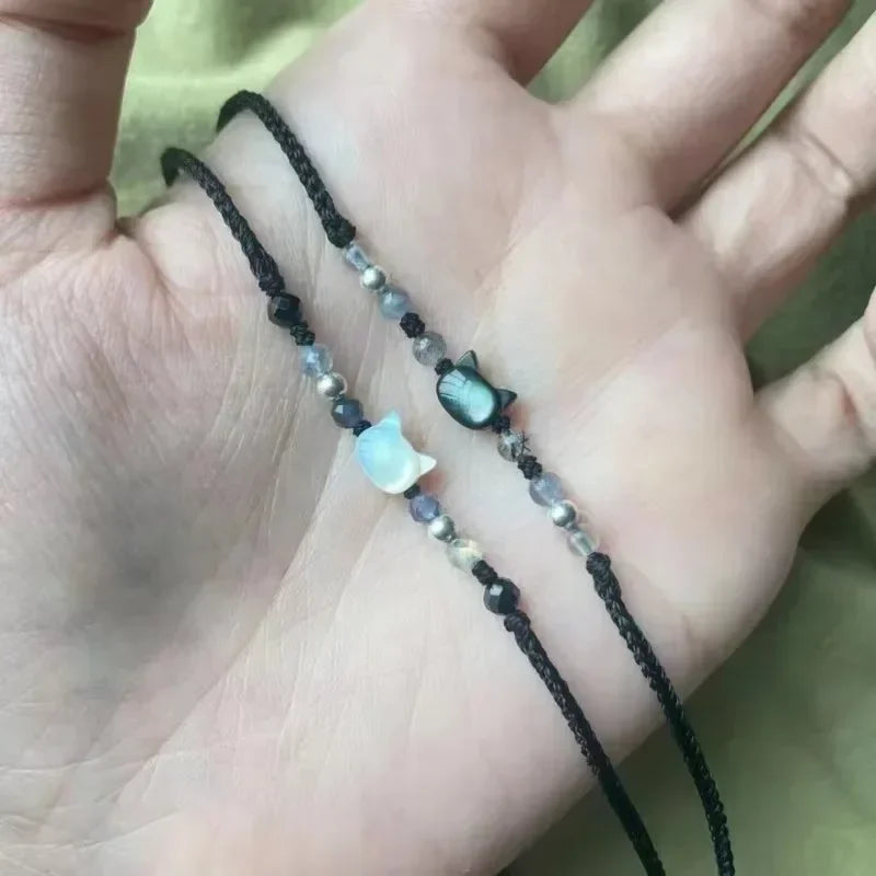 Hand holding a beaded bracelet with a small charm on a blurred background