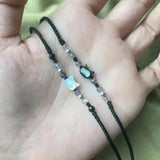 Hand holding a beaded bracelet with a small charm on a blurred background