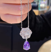 Diamond necklace with purple gemstone held by a hand, brand 'CUMEE' visible