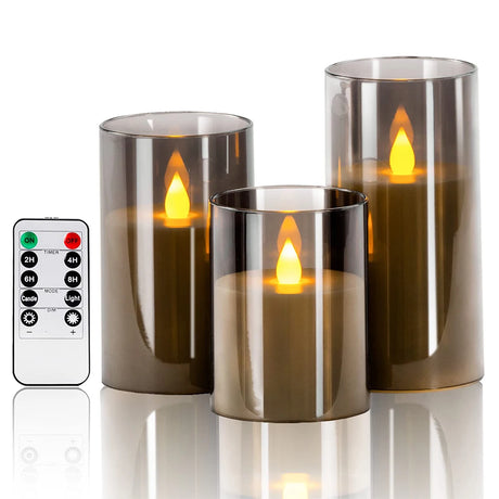 Set of three smoked glass candle holders with glowing candles and a remote control on a white background