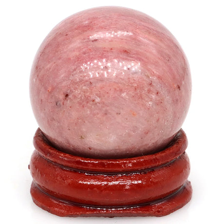 Pink crystal ball on a red stand against a white background