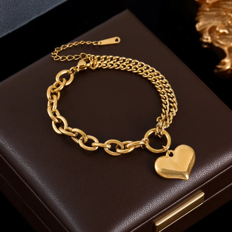 Gold chain bracelet with a heart charm on a dark surface