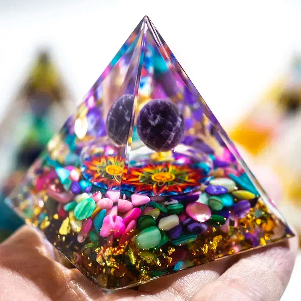 Pyramid-shaped crystal with colorful stones and mandala design on a blurred background