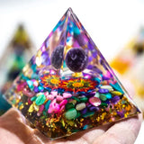 Pyramid-shaped crystal with colorful stones and mandala design on a blurred background