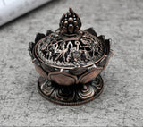 Decorative bronze incense burner with intricate designs on a gray surface
