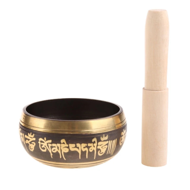 Tibetan singing bowl with gold script and wooden striker on a white background