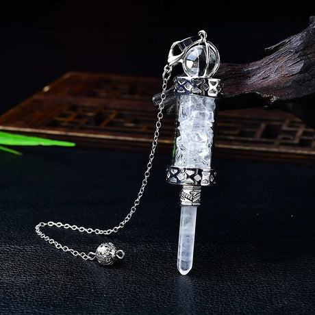 Crystal dagger pendant with chain on a dark surface