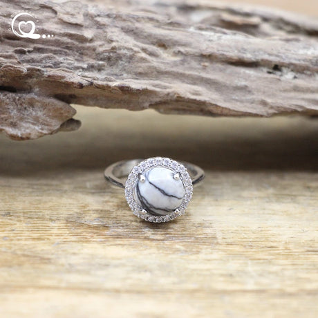 Silver ring with a white stone on a wooden surface