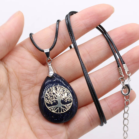 Necklace with a tree of life pendant held in a hand against a white background