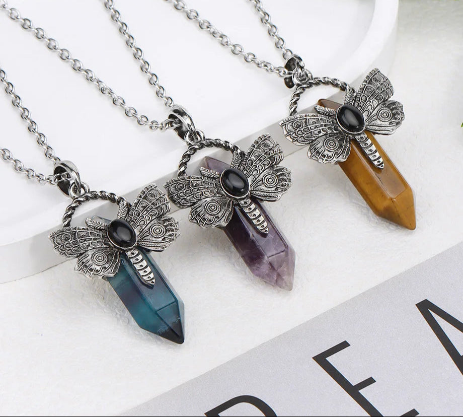 Three crystal pendant necklaces with butterfly designs on a white surface.