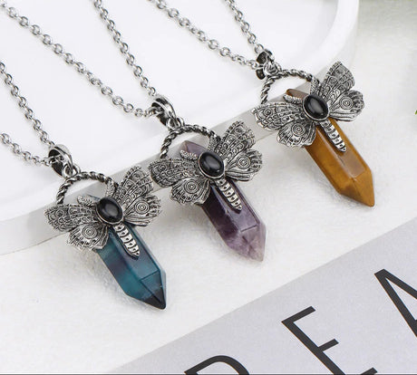 Three crystal pendant necklaces with butterfly designs on a white surface.