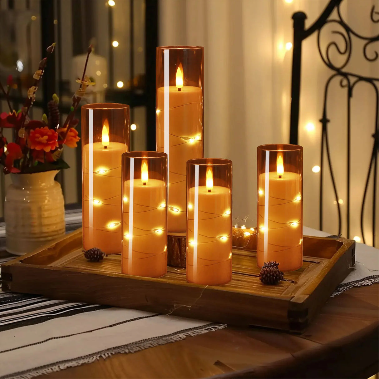 Decorative candles with string lights on a wooden tray in a cozy indoor setting.