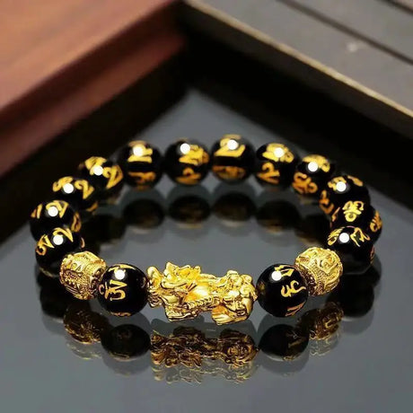 Black and gold beaded bracelet on a reflective surface