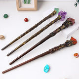 Three decorative wands with ornate handles on a white surface with colorful stones.