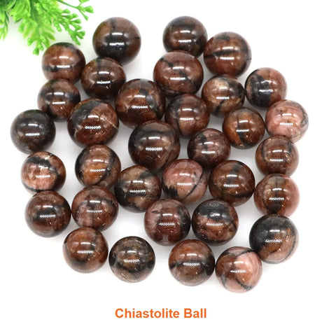Chiastolite balls on a white background with green leaves.