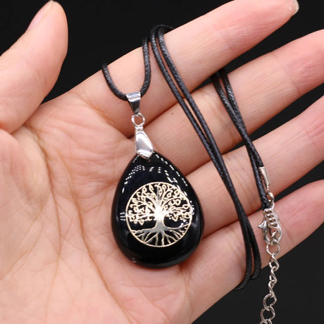 Black pendant with tree of life design on a hand