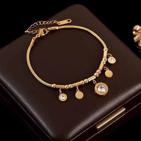 Gold bracelet with charms on a dark brown surface