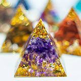 Pyramid-shaped crystal with purple and gold colors on a blurred background