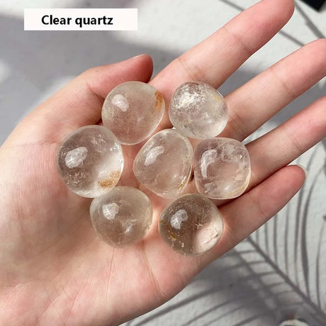 Clear quartz stones held in a hand with a neutral background