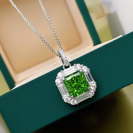 Green gemstone pendant with silver chain on a green surface