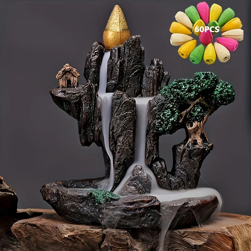 Decorative mountain scene with waterfall and trees, featuring a gold cone on top, against a dark background.