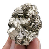 Mineral specimen held between fingers against a white background