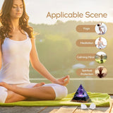 Woman meditating with a purple crystal pyramid on a wooden deck, surrounded by nature.