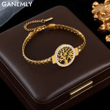 Gold bracelet with tree of life design on a dark surface, featuring the brand 'GANEMLY'.