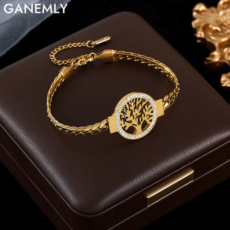 Gold bracelet with tree of life design on a dark surface, featuring the brand 'GANEMLY'.