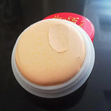Makeup sponge on a black surface with a red container in the background