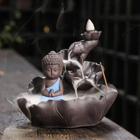 Ceramic incense burner with Buddha figure and lotus design on a dark background