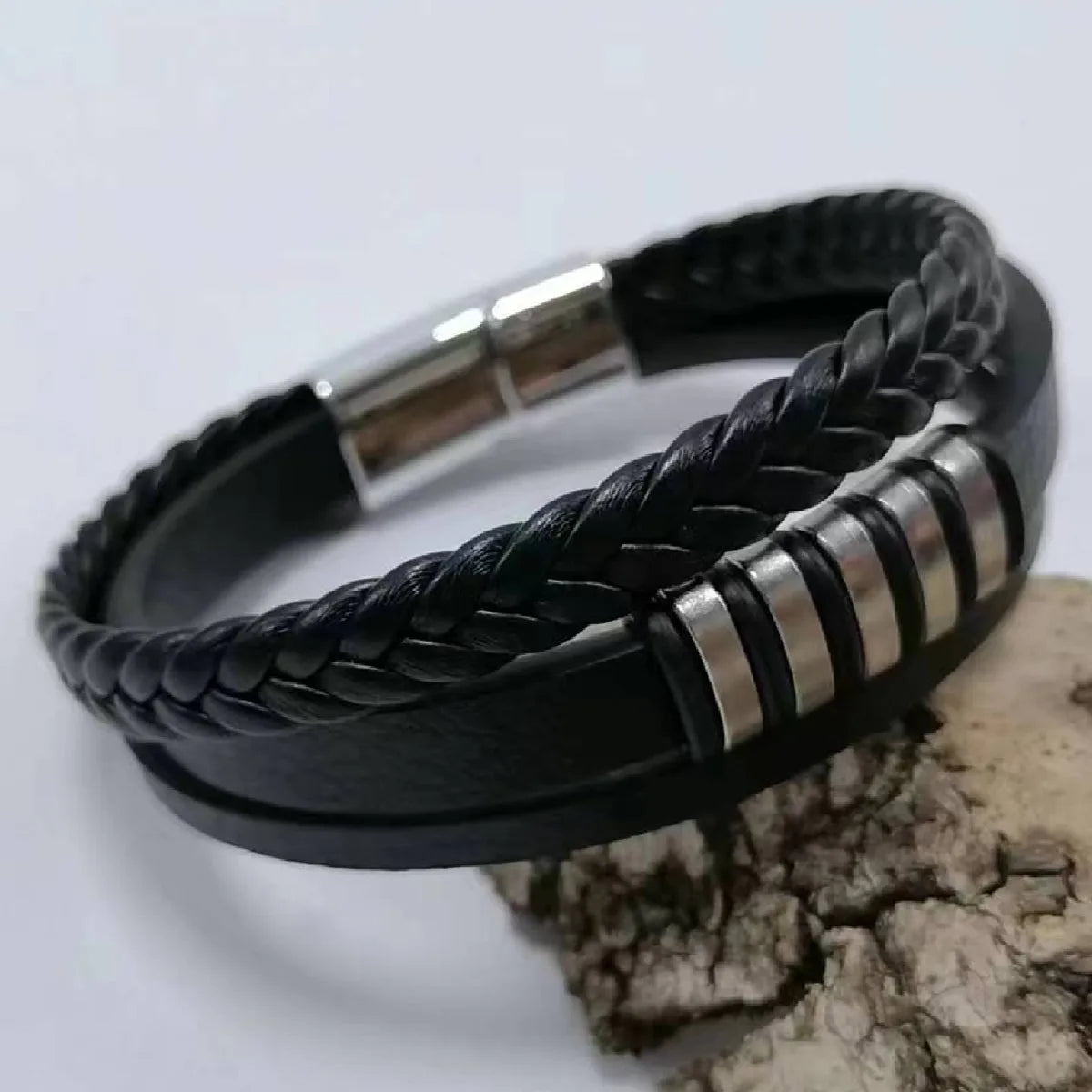 Black braided leather bracelet with silver accents on a light gray background