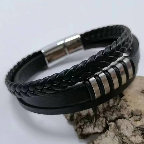 Black braided leather bracelet with silver accents on a light gray background
