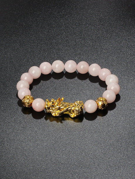 Pink beaded bracelet with gold dragon clasp on a dark background